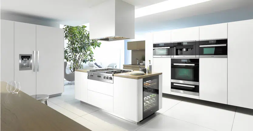 Cuisine ouverte sur salon avec hotte suspendu et de l'électroménager intégrés dans les colonnes