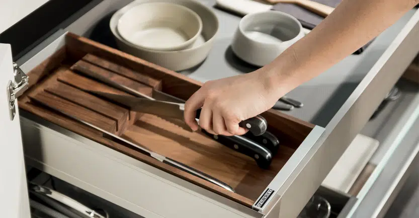 Cuisiniste haut de gamme range des ustensiles de cuisines dans tiroir coulissants avec séparateur